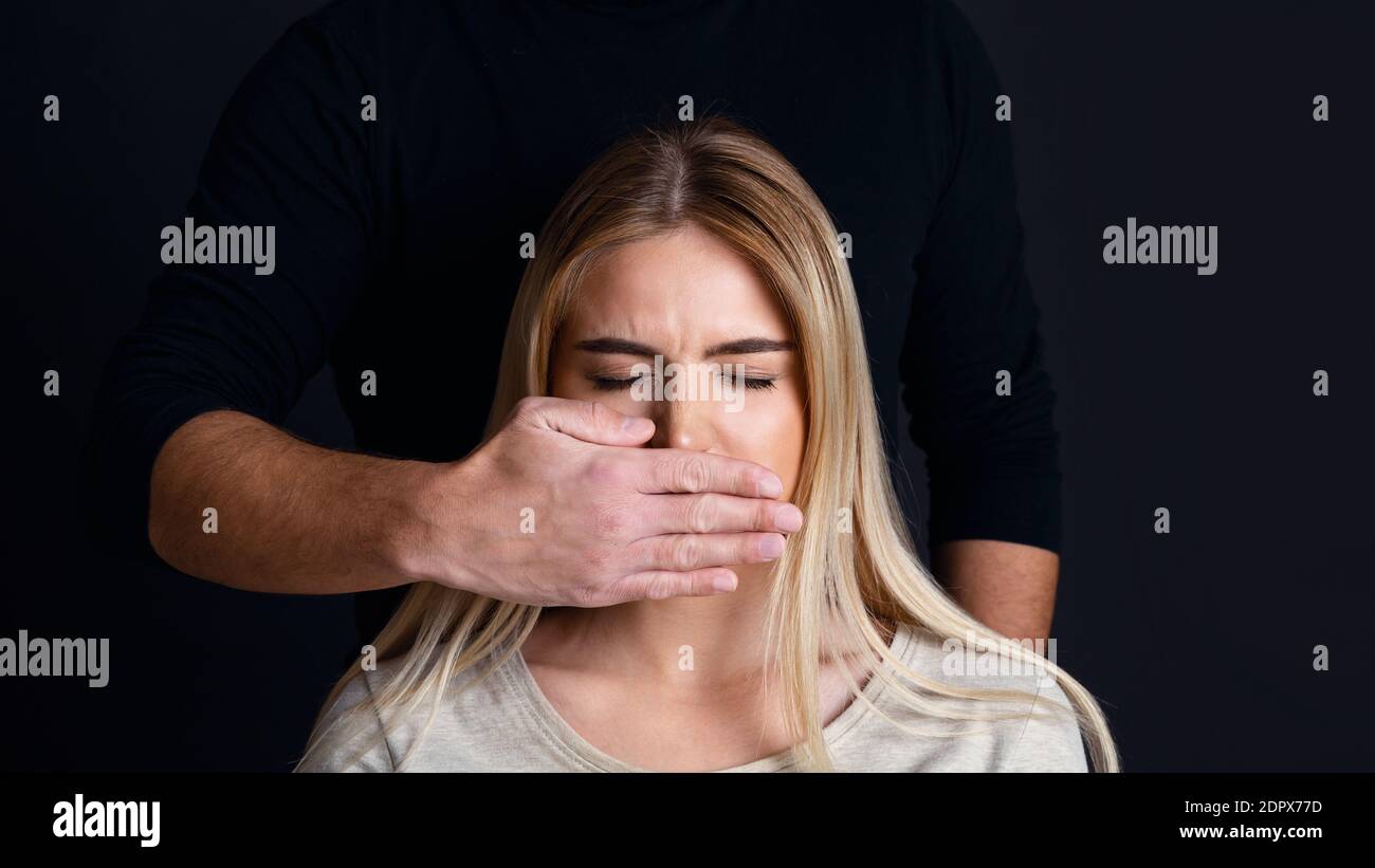 Homme de pression psychologique et physique sur la femme. La main mâle ferme la bouche de la femme Banque D'Images