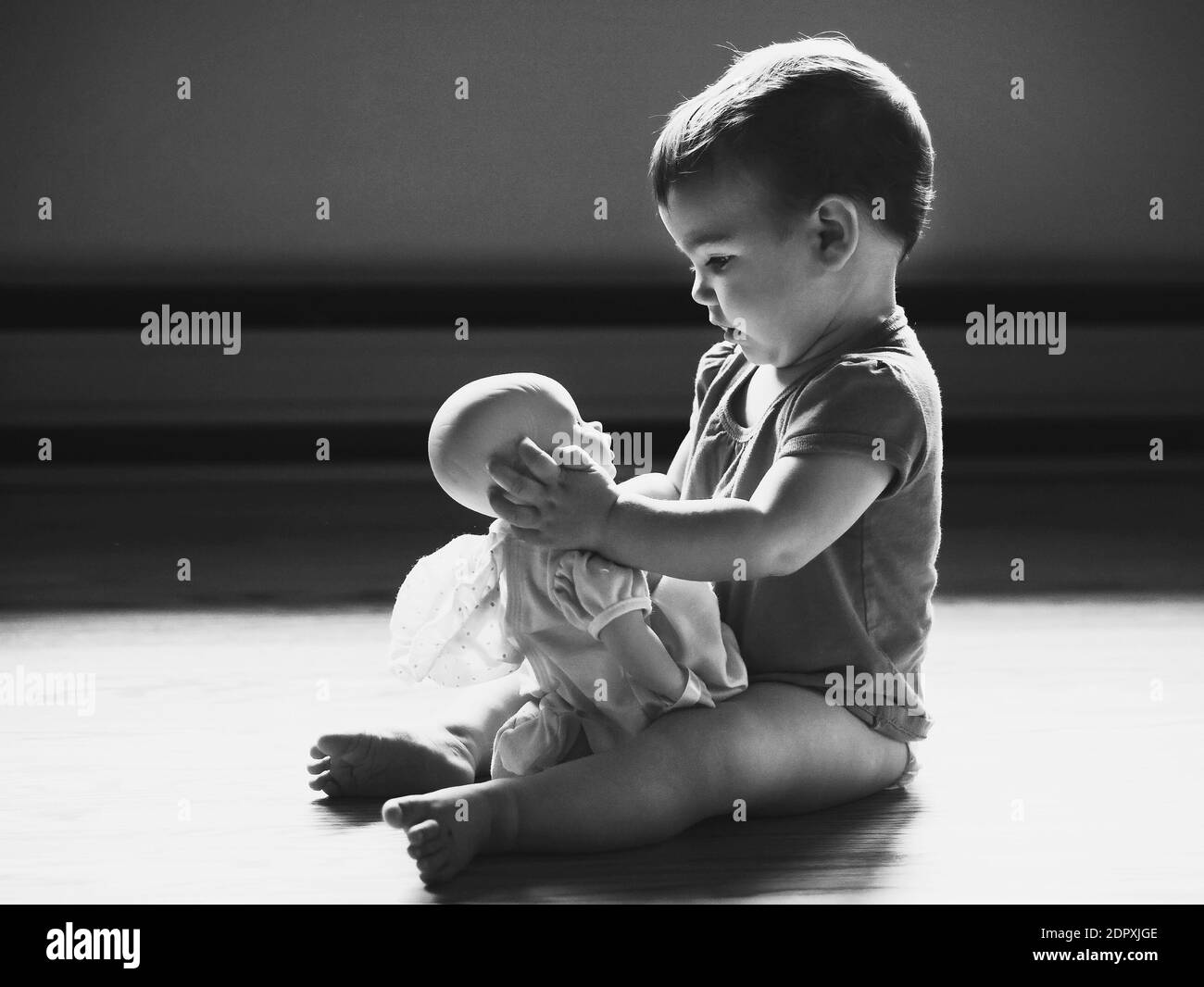 Vue latérale de bébé fille jouant avec une poupée sur le sol Photo Stock -  Alamy