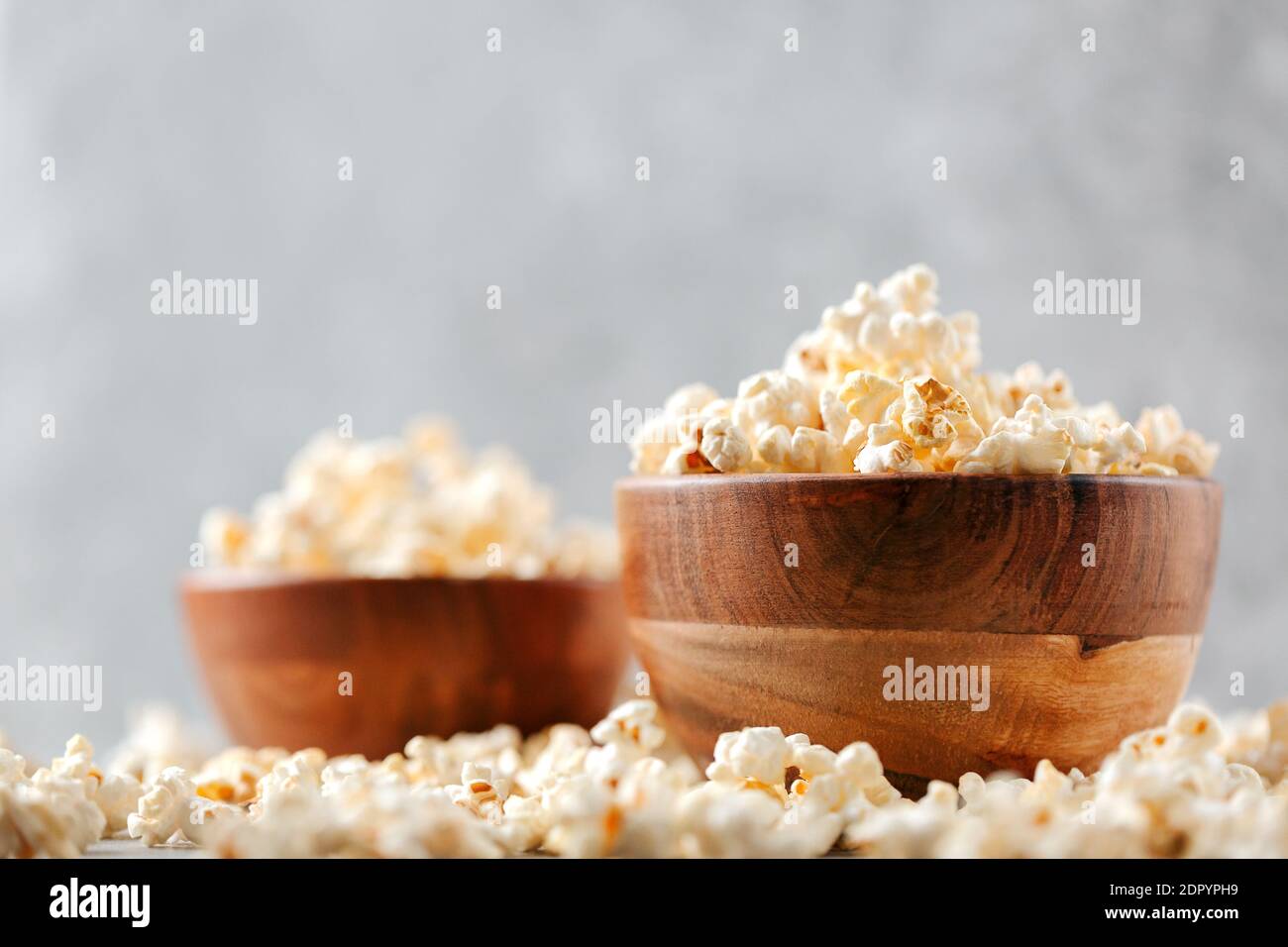 Deux bols en bois de pop-corn salé sur table grise rustique. Mise au point sélective et espace de copie pour le texte. Concept de détente et de repos. Banque D'Images