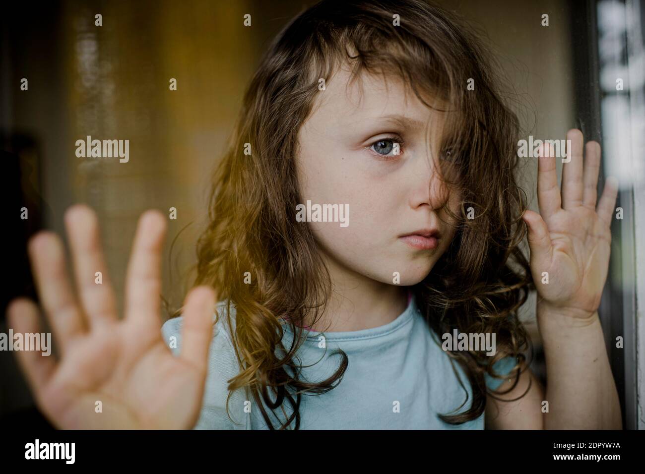 L'enfant regarde malheureusement à travers le volet de fenêtre Banque D'Images