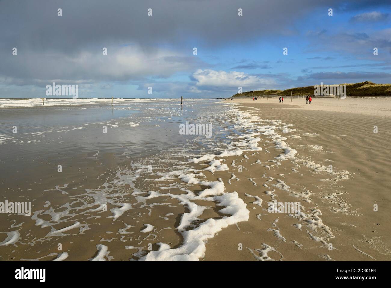 Vue sur la plage nord avec vagues et formation de mousse, les marcheurs de plage à la ligne de rinçage, Mer du Nord, Norderney, îles de Frise orientale, Basse-Saxe Banque D'Images