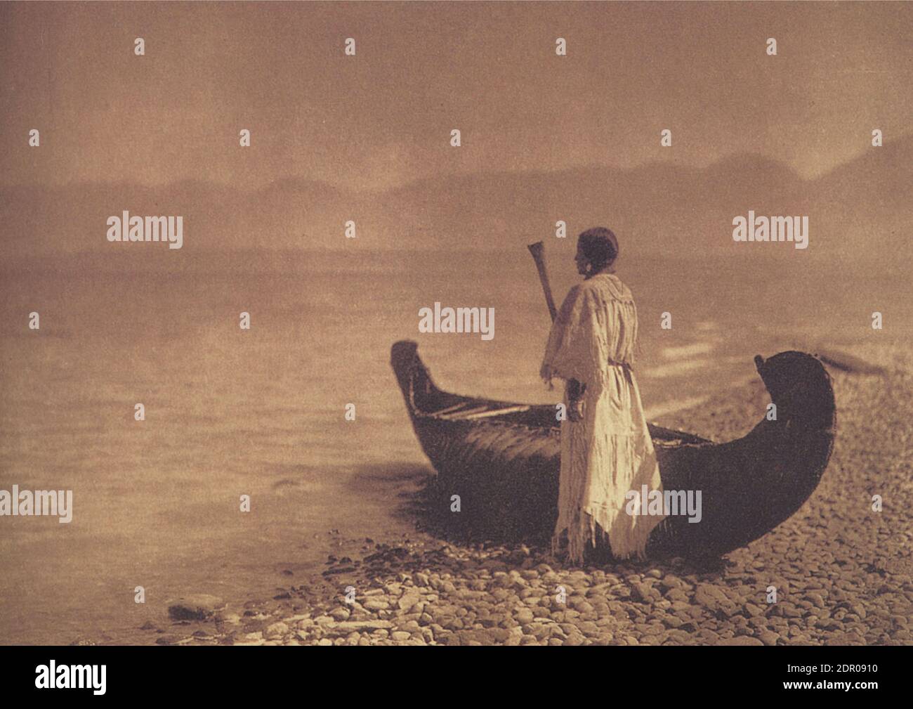 Photographie vintage de la femme Kutenai de 1910 par Edward S Curtis. La femme est debout près de son canot en regardant vers le lac. Peut-être Montana ou Idaho. Banque D'Images