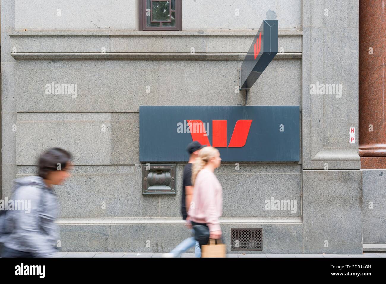 Un symbole Westpac Bank à la hauteur du sentier avec des personnes floues qui passent devant une succursale de la banque de la ville de Sydney en Australie Banque D'Images