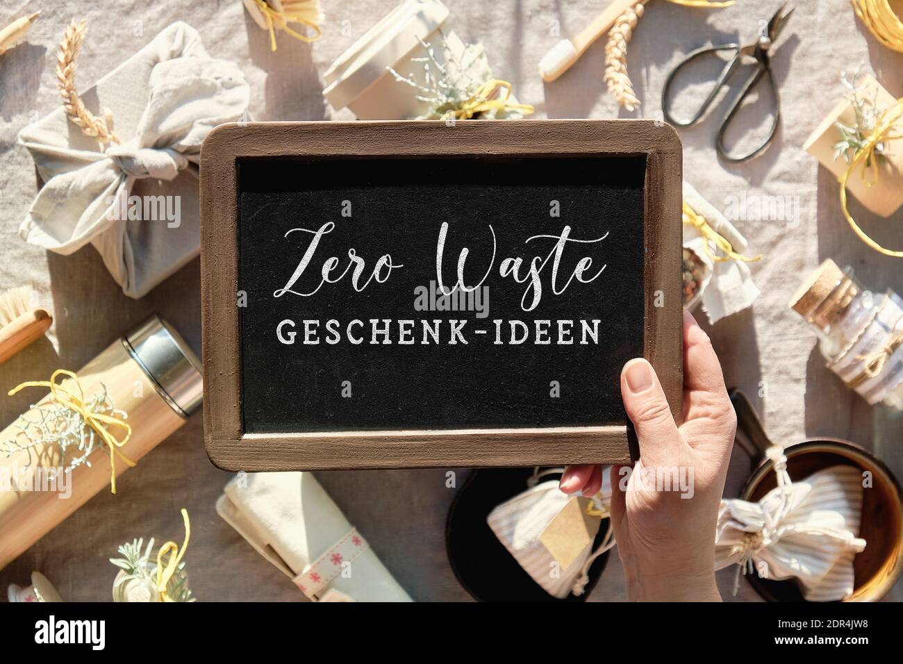 Main tenir le tableau noir avec le texte Zero Waste geschenk-ideen, en  allemand. Cela signifie zéro déchet idées de cadeau en anglais. Des cadeaux  écologiques sur un linge chaud Photo Stock -