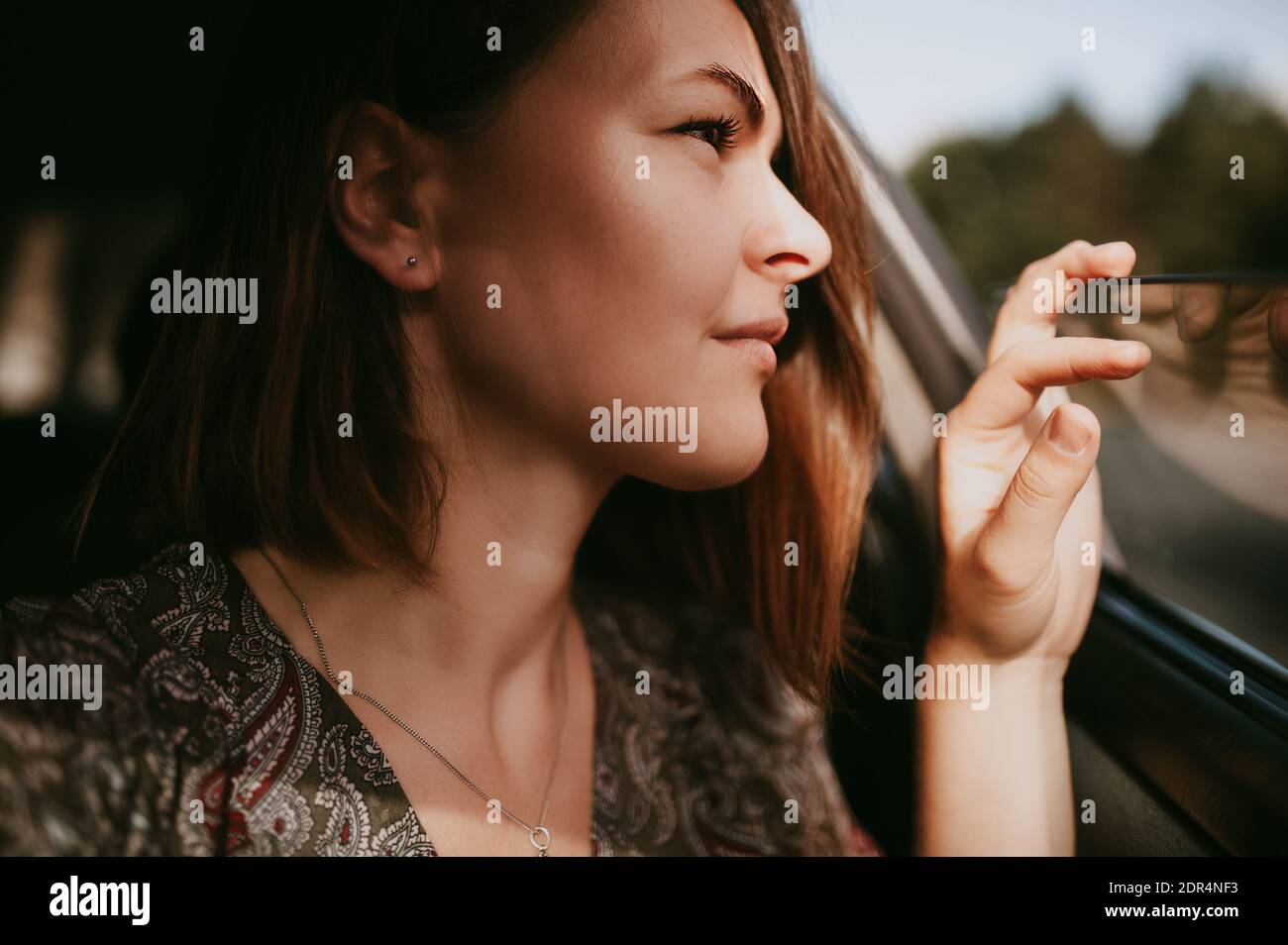 Jeune femme avec cheveux courts foncés et boucles d'oreilles argentées  regarde soigneusement la fenêtre de voiture ouverte Photo Stock - Alamy