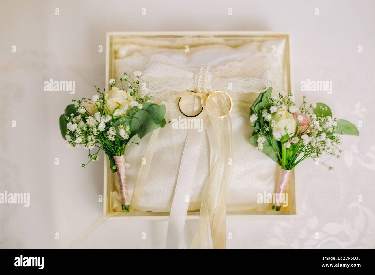 Anneaux d'engagement de mariage dans une boîte spéciale attachée de couleur crémeuse rubans Banque D'Images
