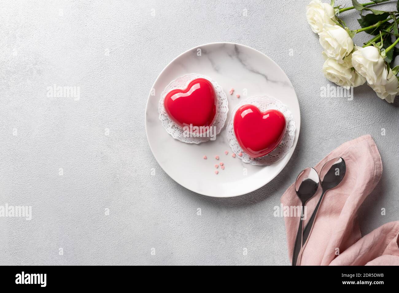 cœur rouge mousse gâteaux et bouquet de roses blanches sur arrière-plan gris Banque D'Images