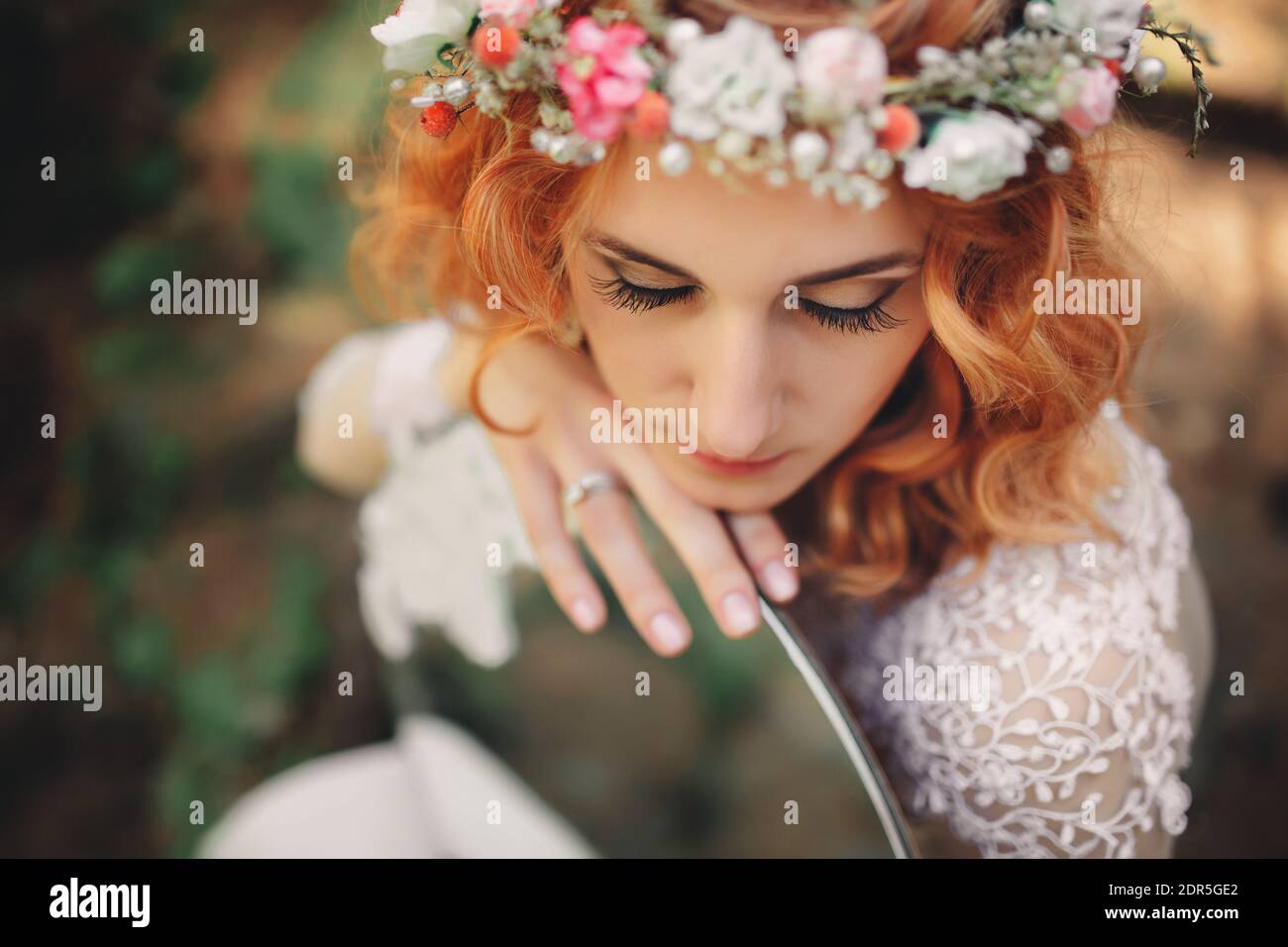 belle jeune mariée aux cheveux rouges dans la forêt avec une couronne florale sur sa tête et miroir . femme en robe blanche longue dehors le jour d'été. mariage Banque D'Images
