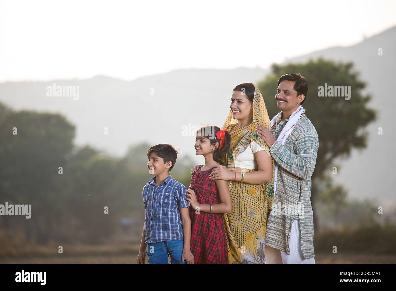 Une famille indienne rurale heureuse qui regarde le champ agricole Banque D'Images