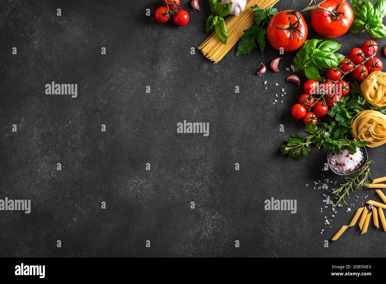 Fond de cuisson des pâtes et légumes non cuits, vue du dessus, espace pour les copies. Diverses pâtes italiennes, tomates, herbes et épices au basilic, conce de cuisine italienne Banque D'Images