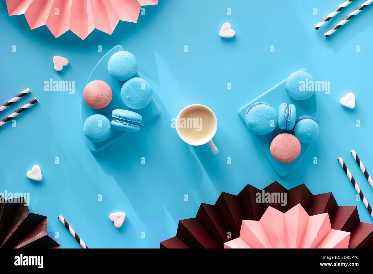 Macrons et café doux et savoureux. Plat créatif sur papier, coloris bleu menthe, rose et noir. Ventilateurs en papier pliés et pailles en papier pour boissons. Naturel Banque D'Images