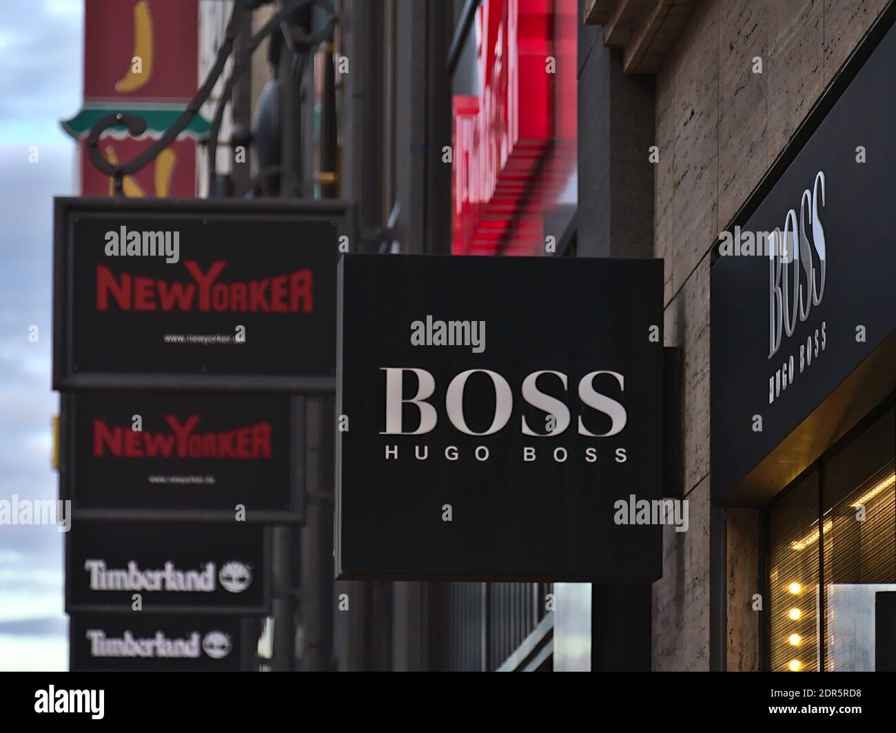 Panneau publicitaire au-dessus de la boutique de la marque allemande de vêtements de détail Hugo Boss dans la rue commerçante Königstraße avec d'autres signes en arrière-plan (New Yorker). Banque D'Images