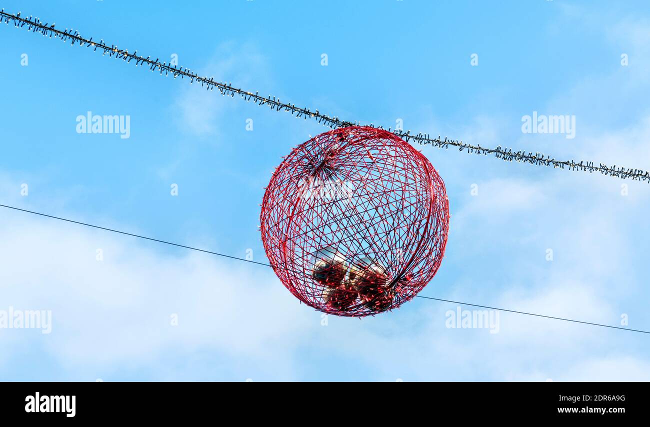 Grande boule de Noël circulaire rouge contre le ciel bleu Banque D'Images