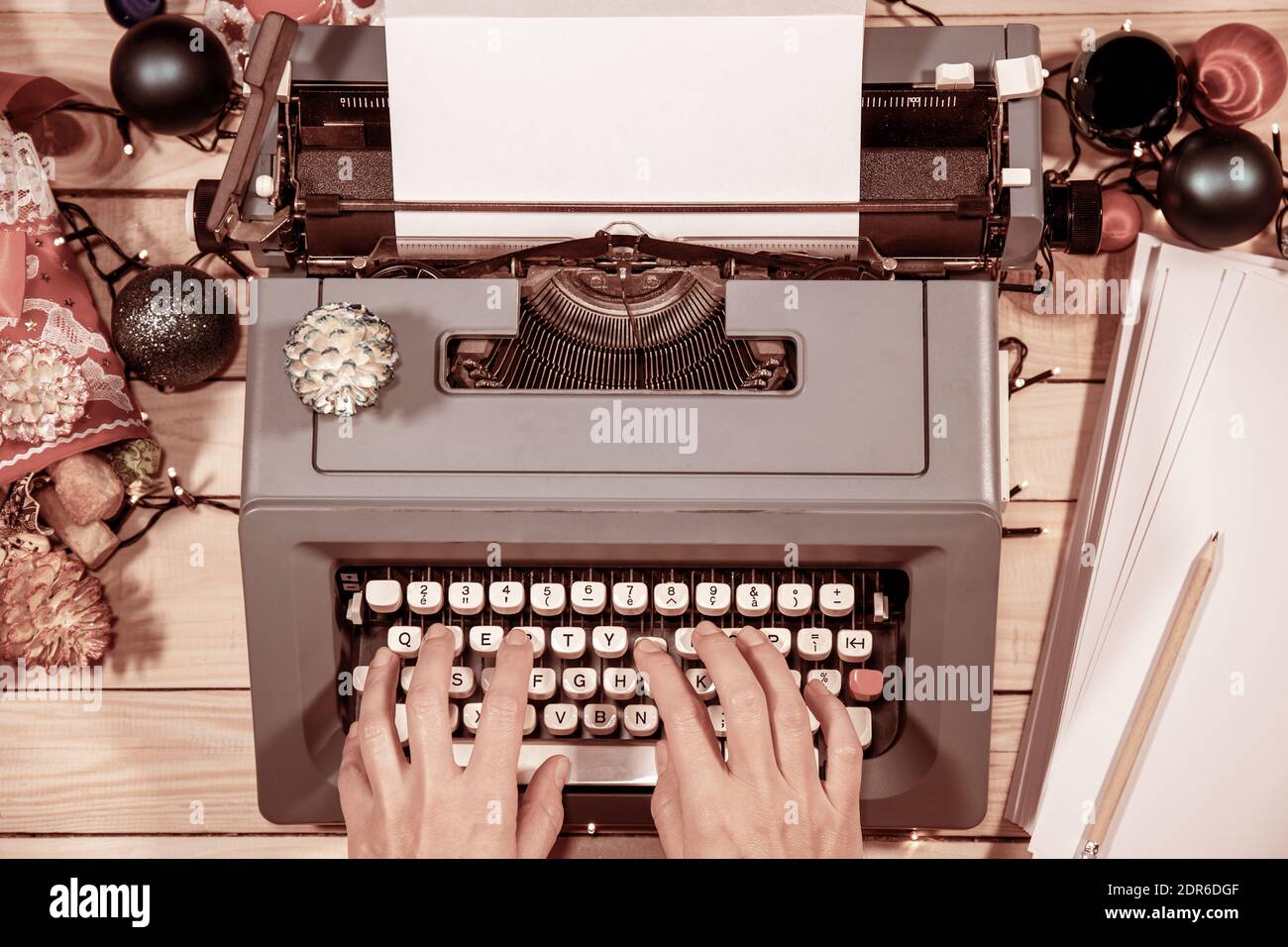 Atmosphère vintage. Taper une lettre ou un manuscrit sur une vieille machine à écrire pendant Noël. Des cônes de pin et des décorations tout autour. Banque D'Images