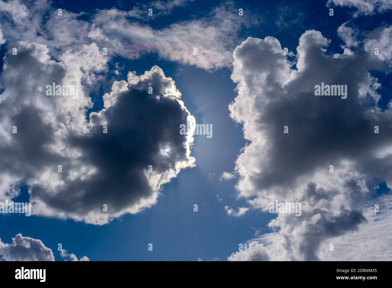 Fond ciel naturel. Nuages gris et blancs moelleux suspendus sur le ciel bleu. Le soleil brille derrière les nuages. Banque D'Images