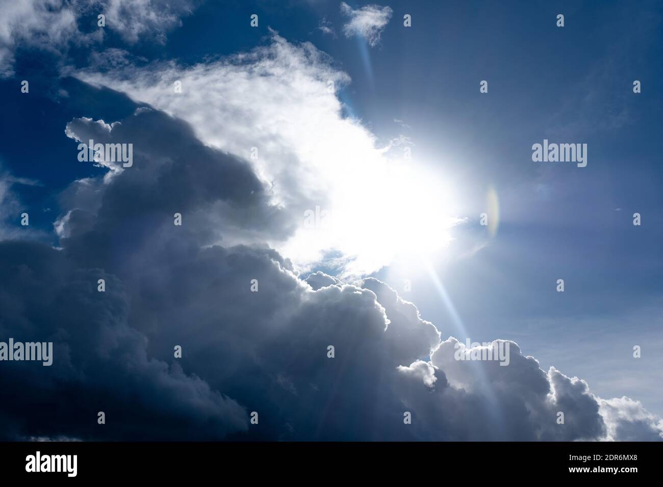 Fond ciel naturel. Nuages gris et blancs moelleux suspendus sur le ciel bleu. Le soleil brille derrière les nuages. Banque D'Images