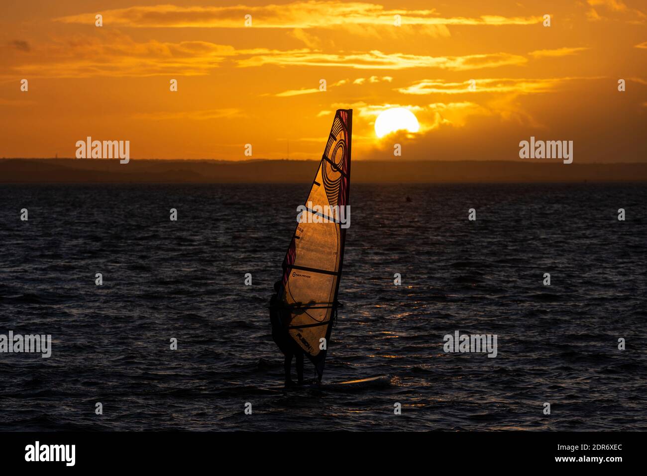 Planche à voile au coucher du soleil le premier jour de l'alerte COVID de niveau 4 à Southend on Sea, Essex, Royaume-Uni. Personne planche à voile pendant que le soleil descend sous le ciel orange Banque D'Images