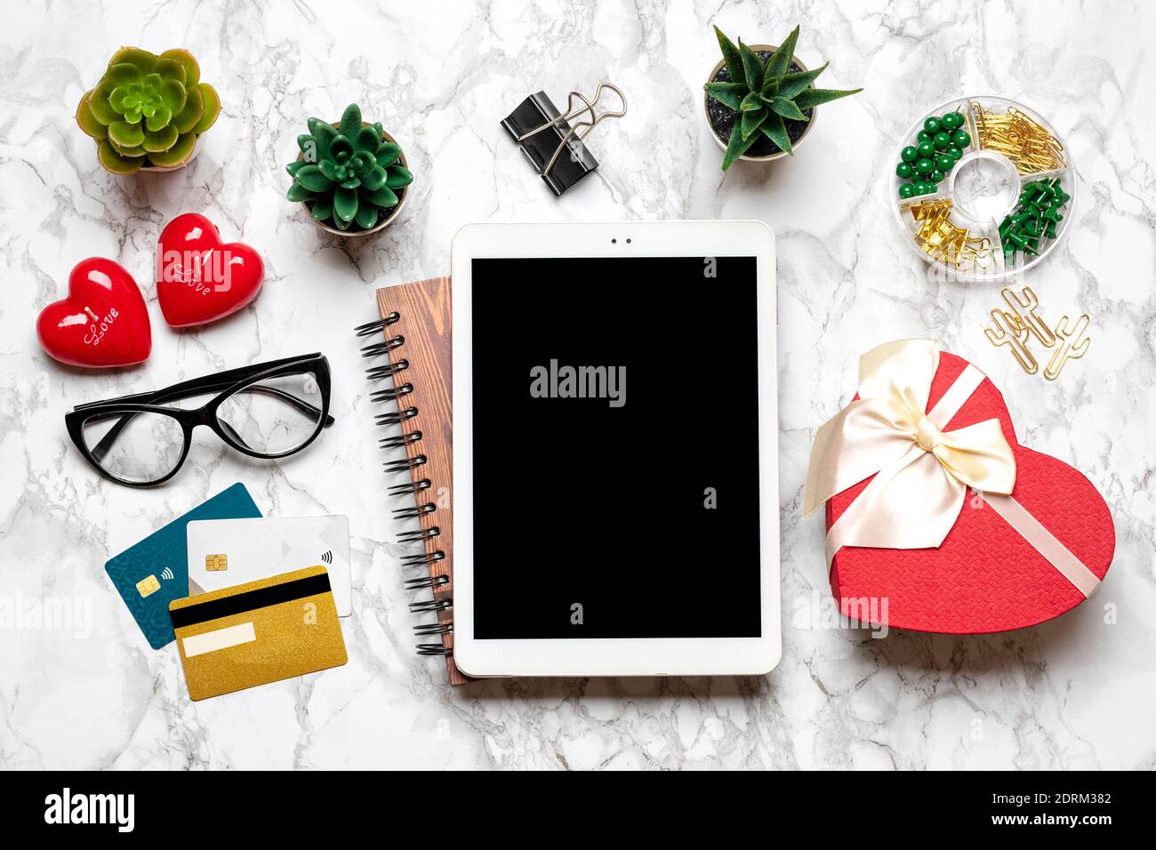 Tablette pour choisir des cadeaux, faire l'achat, tasse de café, carte de débit, boîte, sac, deux coeurs sur table en marbre vue du dessus plat Lay liste d'achats de vacances Banque D'Images