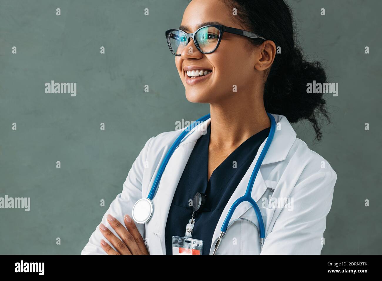 Portrait d'un beau médecin heureux avec un stéthoscope au mur. Jeune médecin spécialiste portant un uniforme et souriant à l'intérieur. Banque D'Images