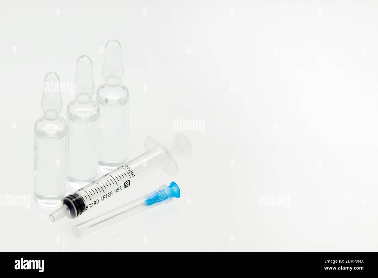 Ampoules de médecine en verre avec seringue liquide et en plastique avec aiguille, isolées sur fond blanc Banque D'Images