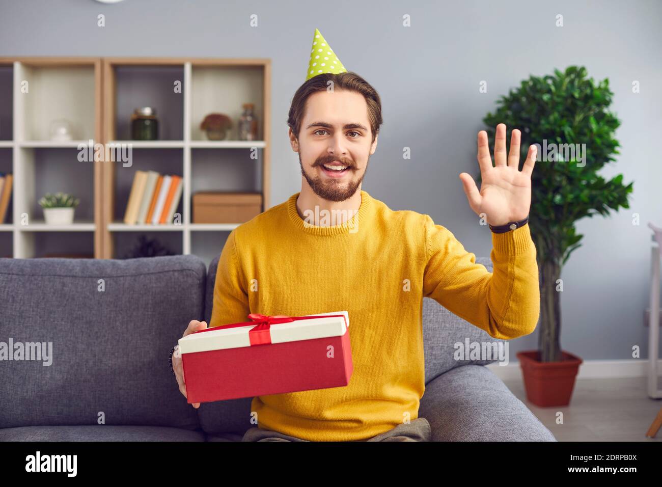 Homme souriant avec boîte cadeau de vacances à la main regardant appareil photo et enregistrement vidéo Banque D'Images