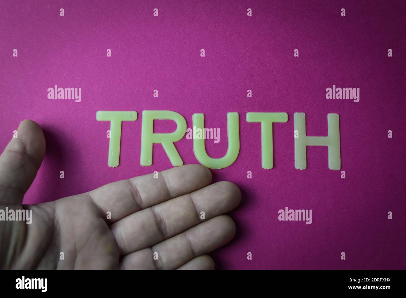 Main humaine montrant le mot vérité écrit avec des lettres en plastique sur un fond de papier rose vif, concept Banque D'Images
