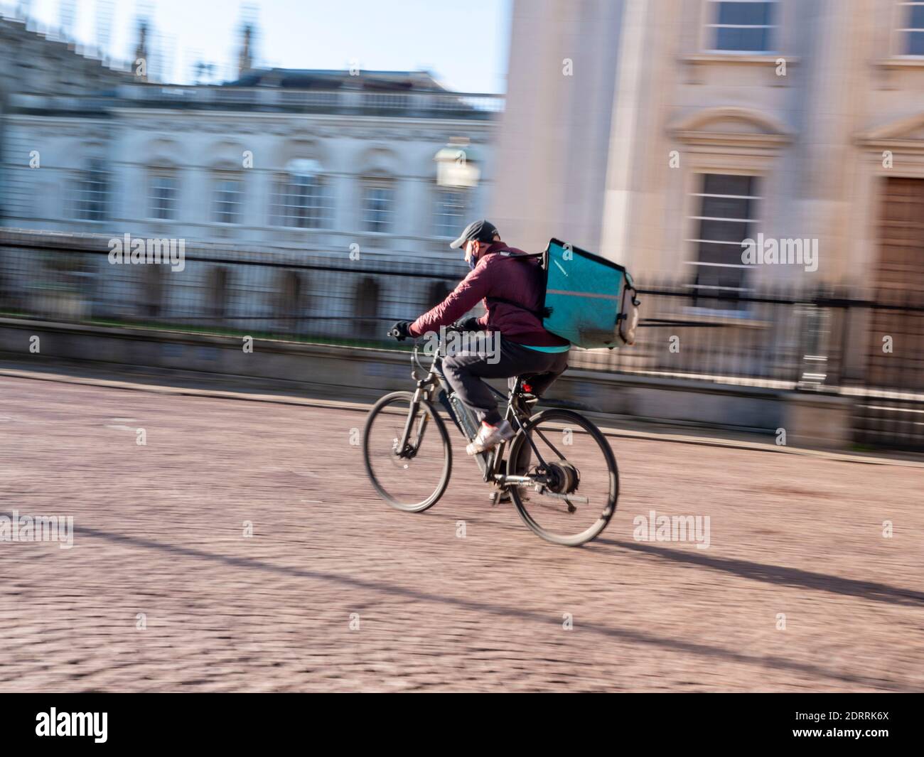 Un cycliste qui passe devant les buidlings de l'université à Kings Défilez à Cambridge au Royaume-Uni sous le soleil d'hiver et laissez-vous séduire par la chaleur flou de mouvement Banque D'Images