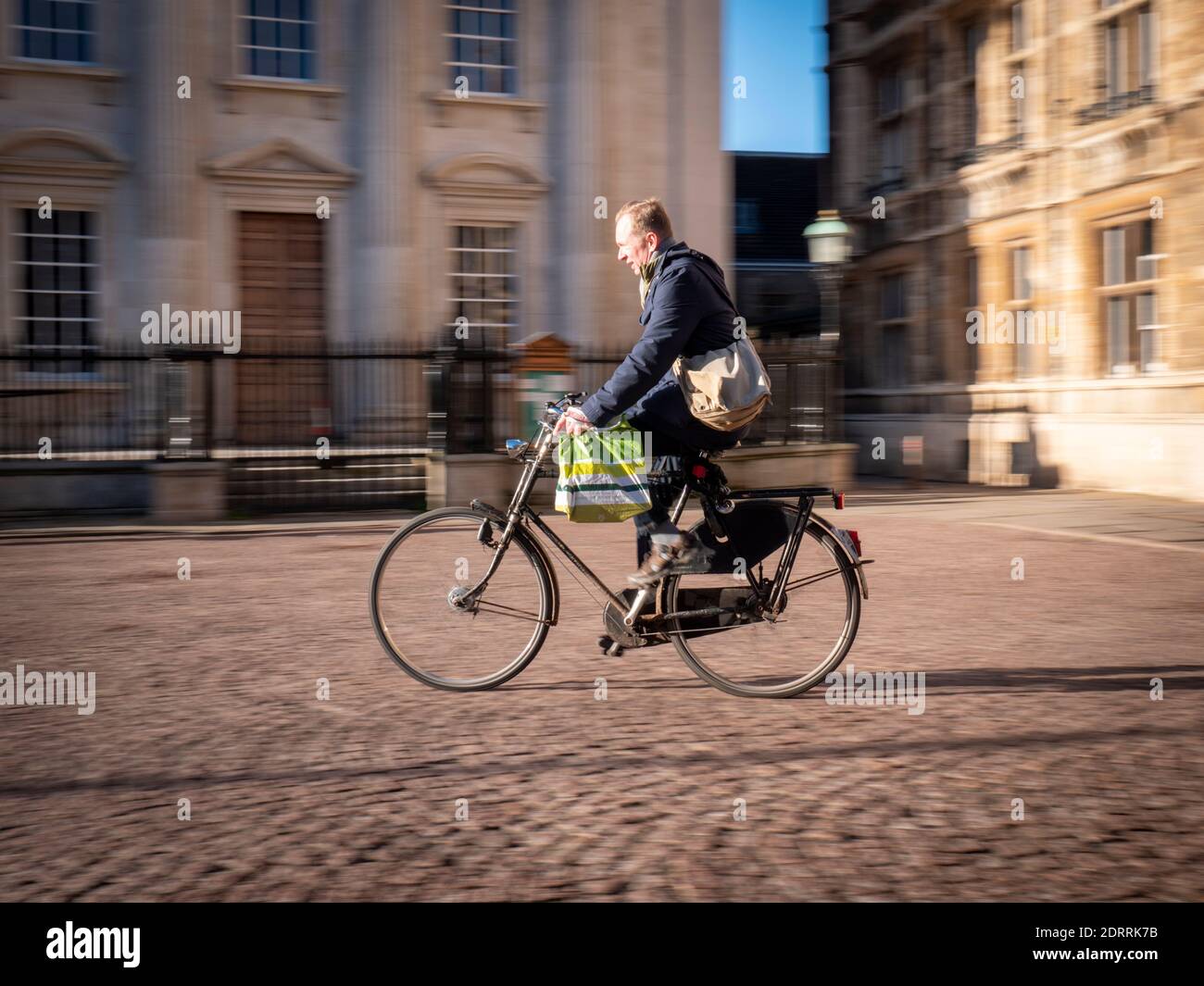 Un cycliste qui passe devant les buidlings de l'université à Kings Défilez à Cambridge au Royaume-Uni sous le soleil d'hiver et laissez-vous séduire par la chaleur flou de mouvement Banque D'Images