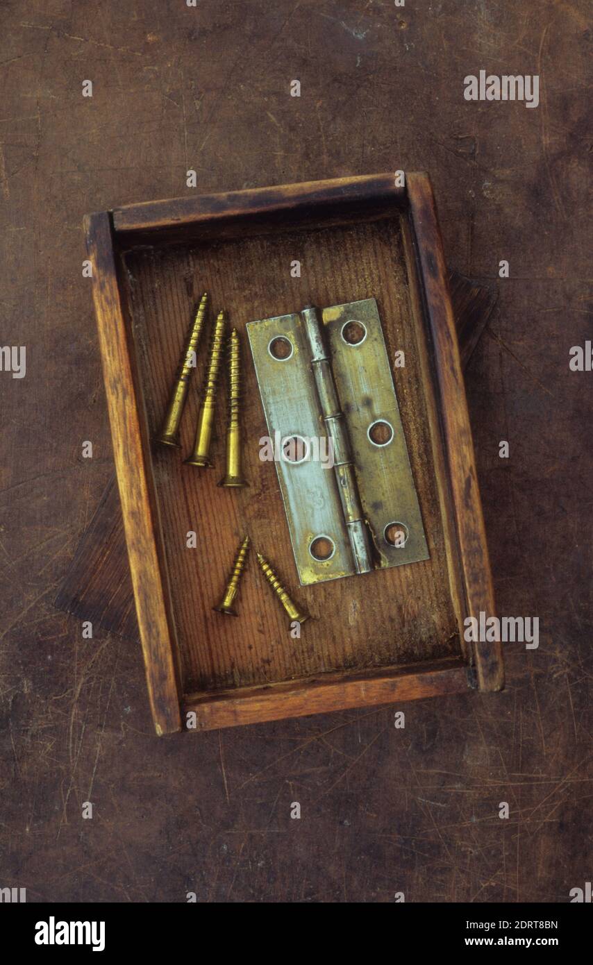 Petite ancienne boîte en bois contenant une charnière de porte en laiton terni et vis en laiton utilisées Banque D'Images Petite ancienne boîte en bois contenant une charnière de porte en laiton terni et vis en laiton utilisées Banque D'Images