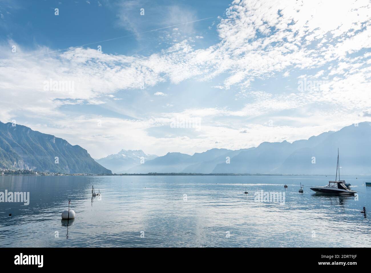 Lac alpin avec eau calme et bateau amarré et entouré de sommets enneigés Banque D'Images
