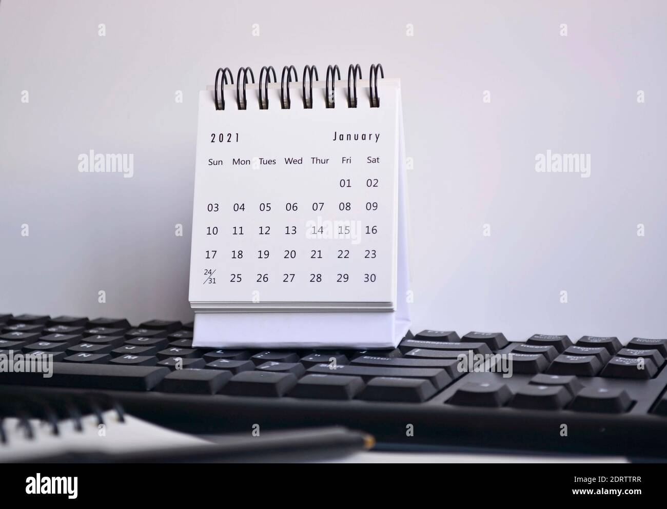 Calendrier blanc de janvier 2021 sur un clavier flou, suspension et ordinateur portable avec arrière-plan blanc. Concept de la nouvelle année Banque D'Images