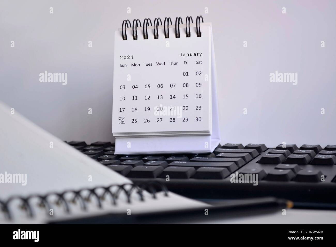 Calendrier blanc de janvier 2021 sur un clavier flou, suspension et ordinateur portable avec arrière-plan blanc. Concept de la nouvelle année Banque D'Images