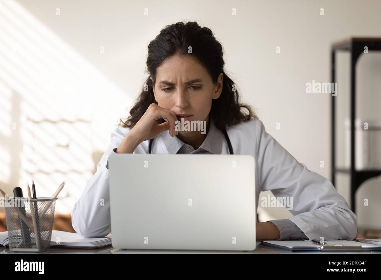 Une femme pensive médecin travaille sur la pensée d'un ordinateur portable Banque D'Images
