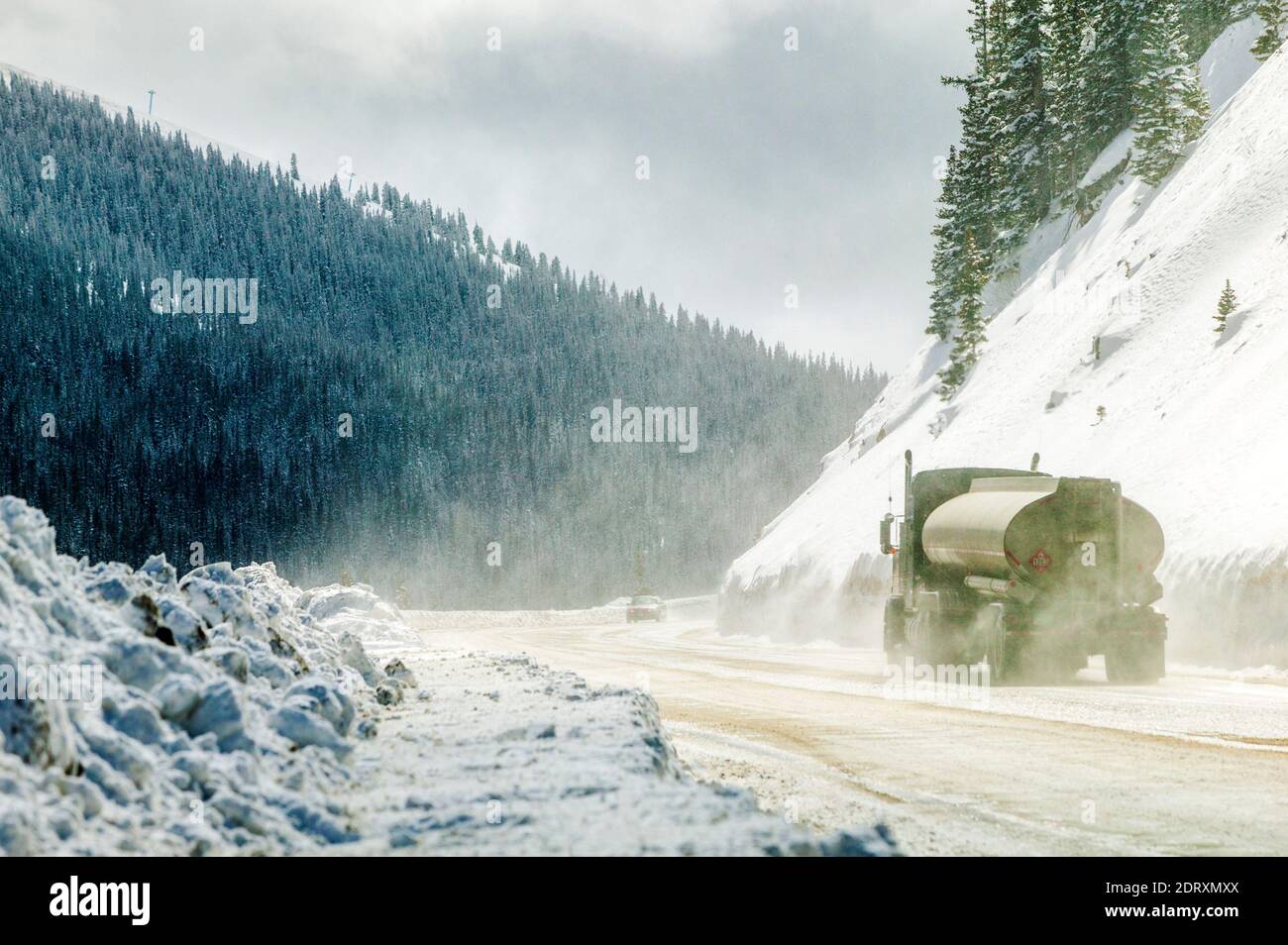 Remorque de tracteur et automobile sur une route hivernale enneigée par le vent; col Monarch; montagnes Rocheuses; centre du Colorado; États-Unis Banque D'Images