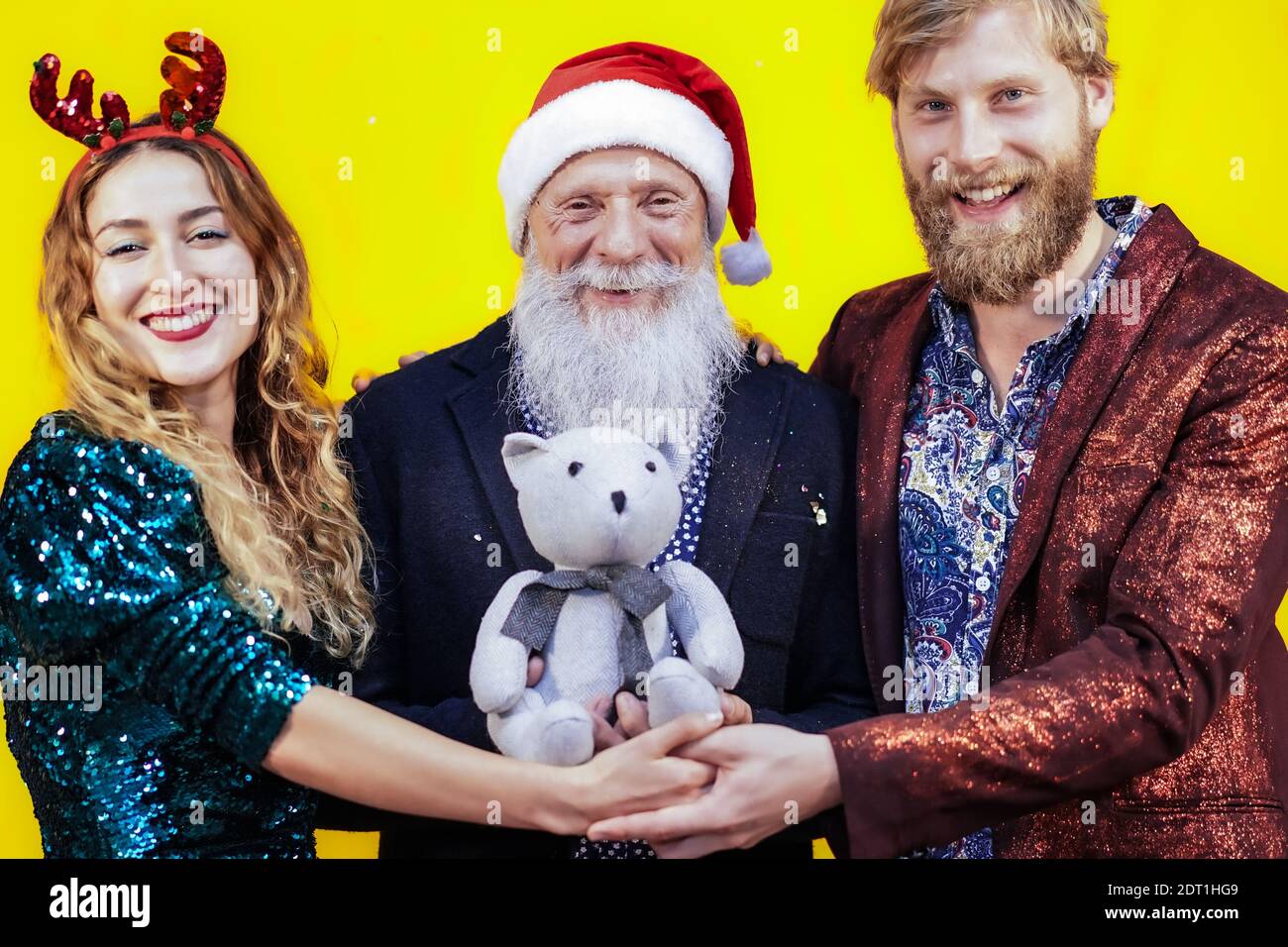 Les personnes avec un petit ours en peluche lors de la fête de noël. Différents amis s'amusent à Noël. Concept de tendance drôle. Banque D'Images