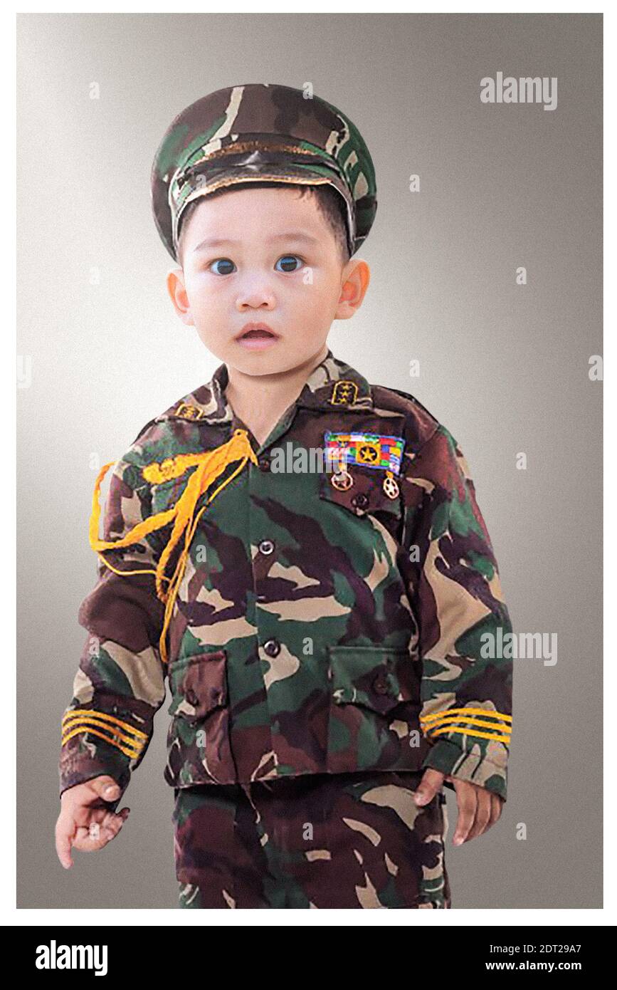 Portrait de bébé garçon dans des vêtements de camouflage debout contre fond  gris Photo Stock - Alamy