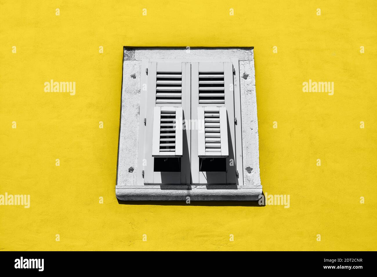 Magnifique cadre de fenêtre ancienne avec des volets en bois gris et un mur jaune lumineux. Cadre de fenêtre rural ou ancien. Elément de conception. Modèle ou m Banque D'Images