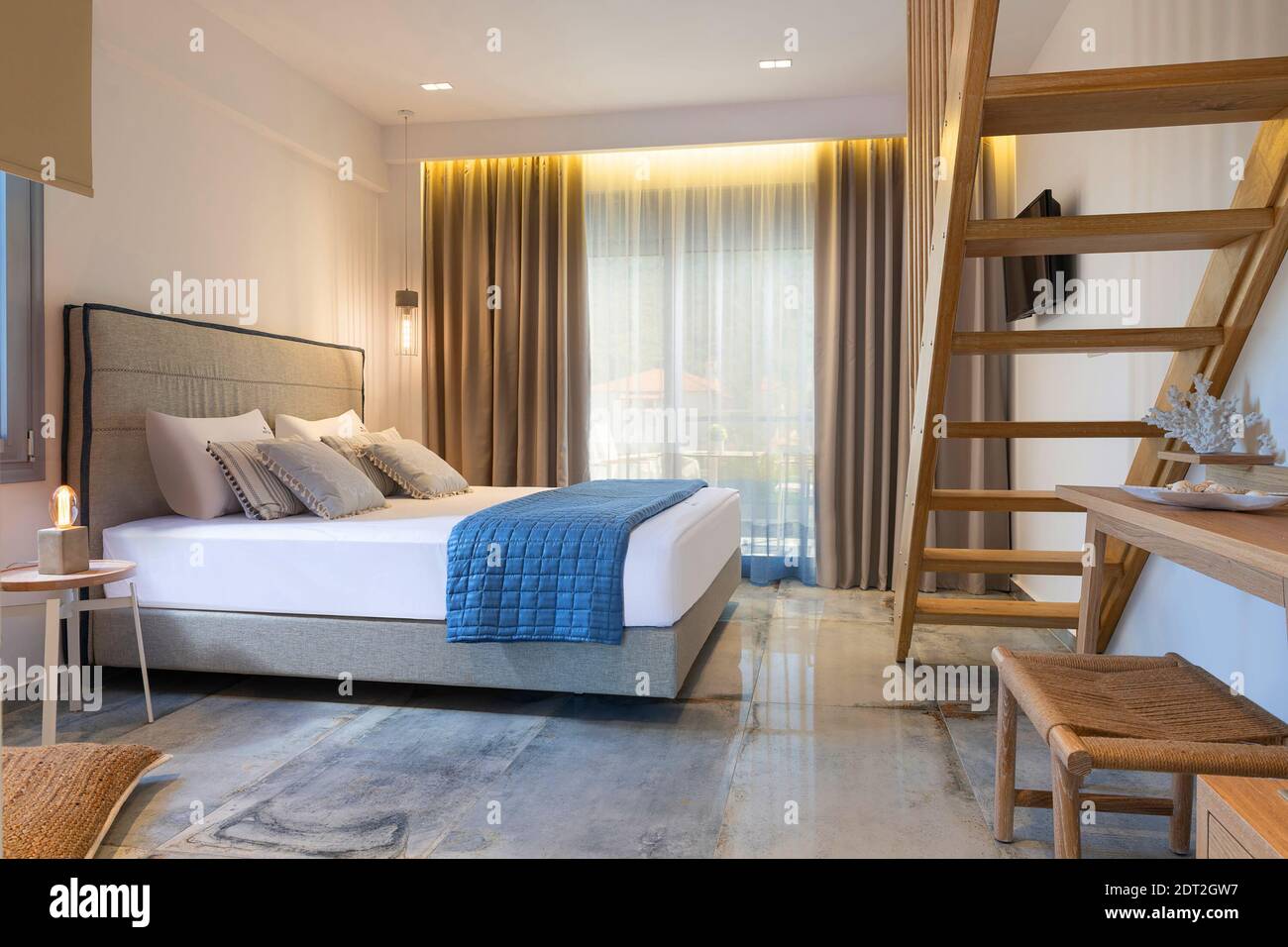 Intérieur moderne de style nautique de l'appartement de l'hôtel, chambre blanche avec échelle en pin, mobilier en bois artisanal, lit double en tissu doux gris Banque D'Images