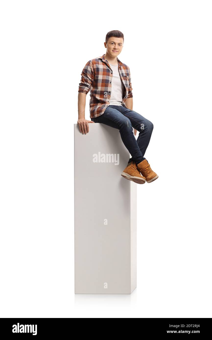 Teenag Guy assis sur une colonne blanche et souriant caméra isolée sur fond blanc Banque D'Images
