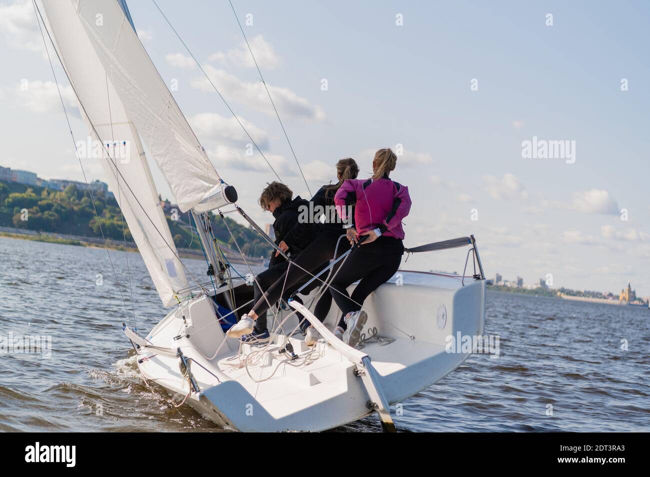 Un yacht rapide, sportif, à un seul mâts avec trois athlètes à bord des voiles avec un vent équitable sur une belle rivière Banque D'Images