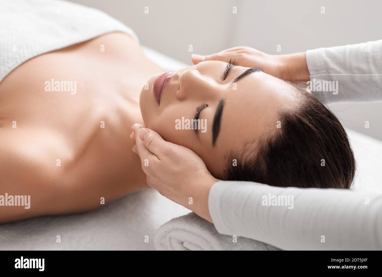 Jeune femme asiatique se détendant pendant la séance de massage du visage à la beauté salon de spa Banque D'Images