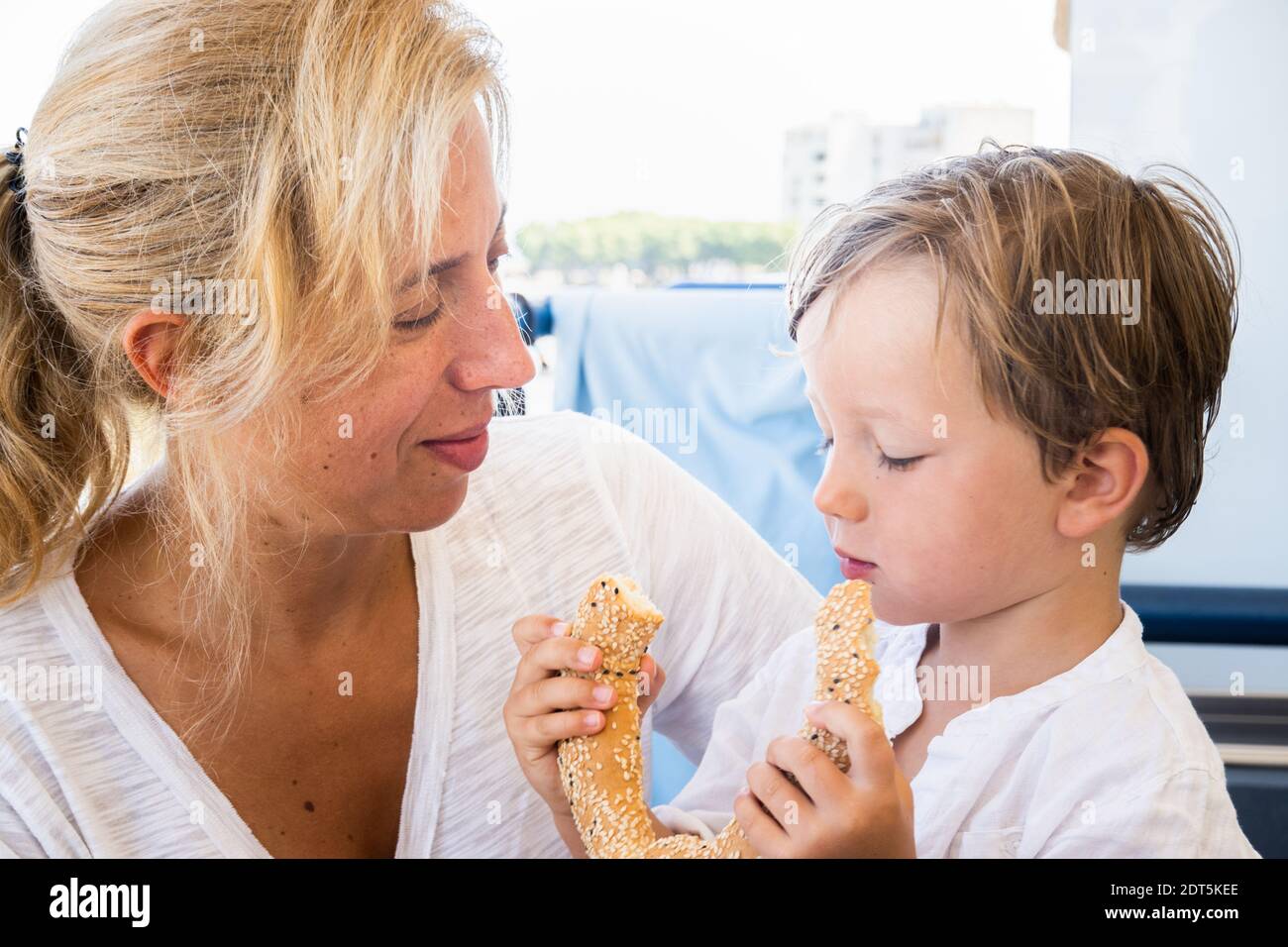 Jeune garçon tenant le bretzel tandis que la mère le regarde Banque D'Images