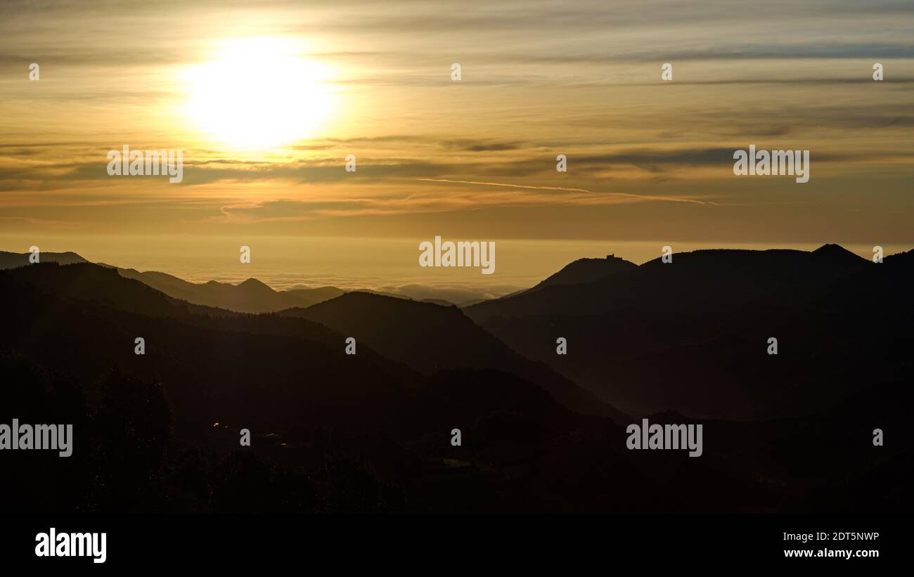 Soleil jaune qui brille sur un lever de soleil matinal au-dessus d'un paysage de nuages sur une silhouette de sommet de montagne Banque D'Images