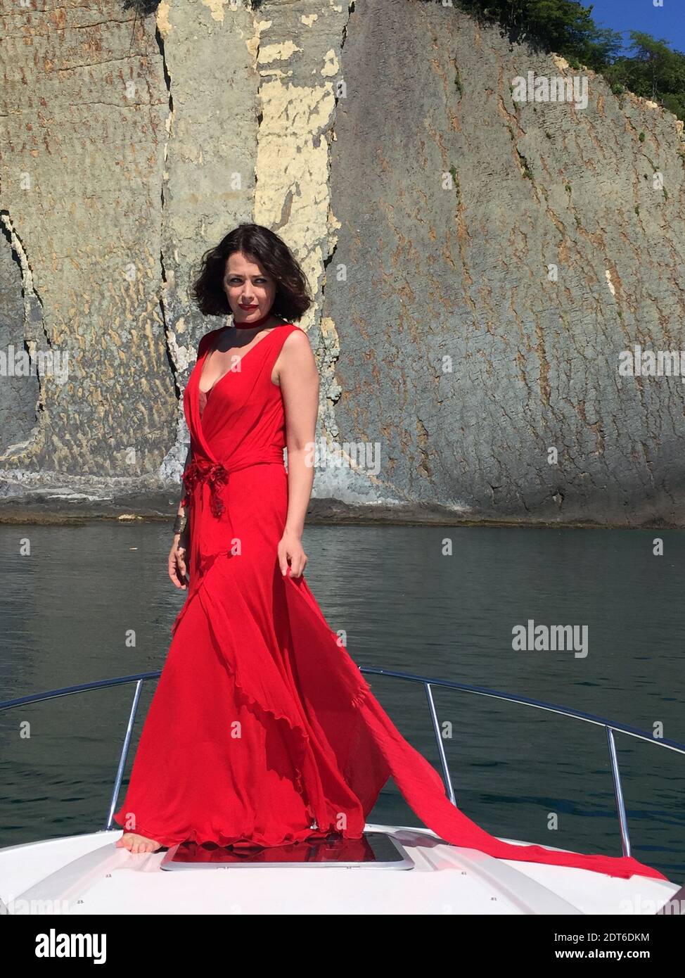 Femme mature en robe rouge debout en bateau contre la ...