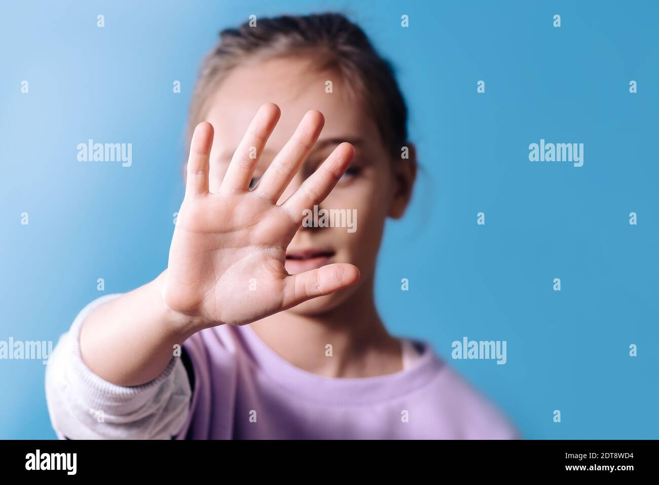 Signe de protestation.fille avec main devant le visage avec un geste d'arrêt sur fond bleu. Copier l'espace Banque D'Images