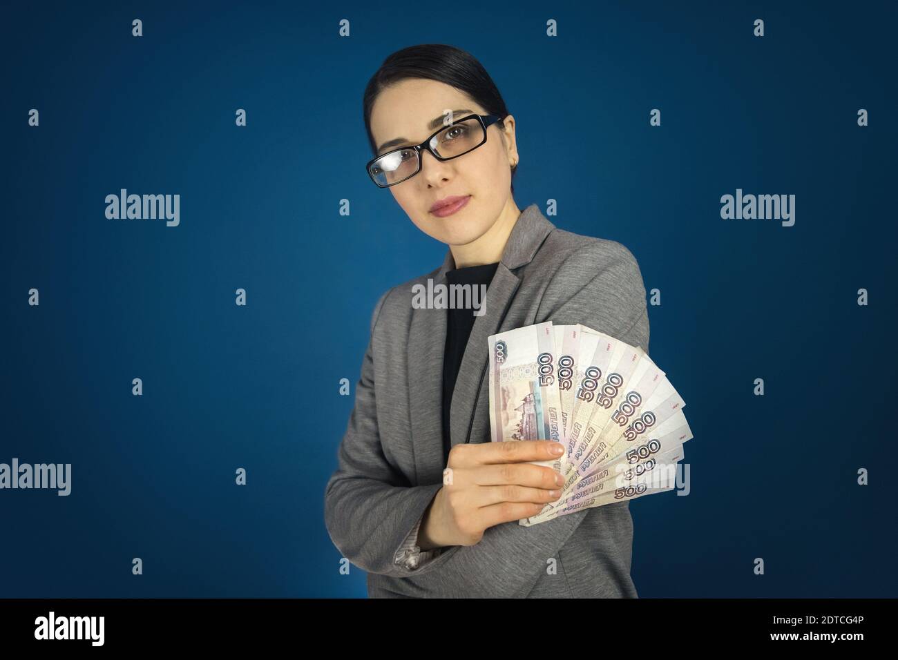 Belle jeune femme en lunettes tient beaucoup de roubles russes dans ses mains. Banque D'Images