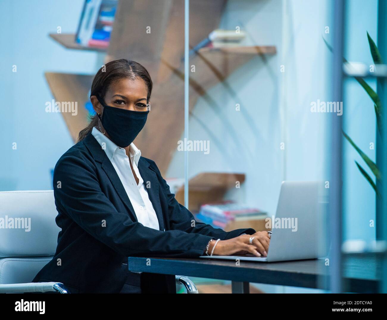 Portrait d'une femme d'affaires portant un masque de travail sur un ordinateur portable à bureau Banque D'Images