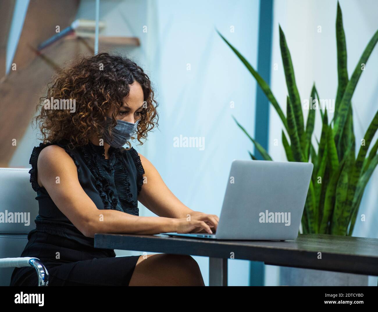 Femme d'affaires portant un masque de protection travaillant sur un ordinateur portable au bureau bureau Banque D'Images