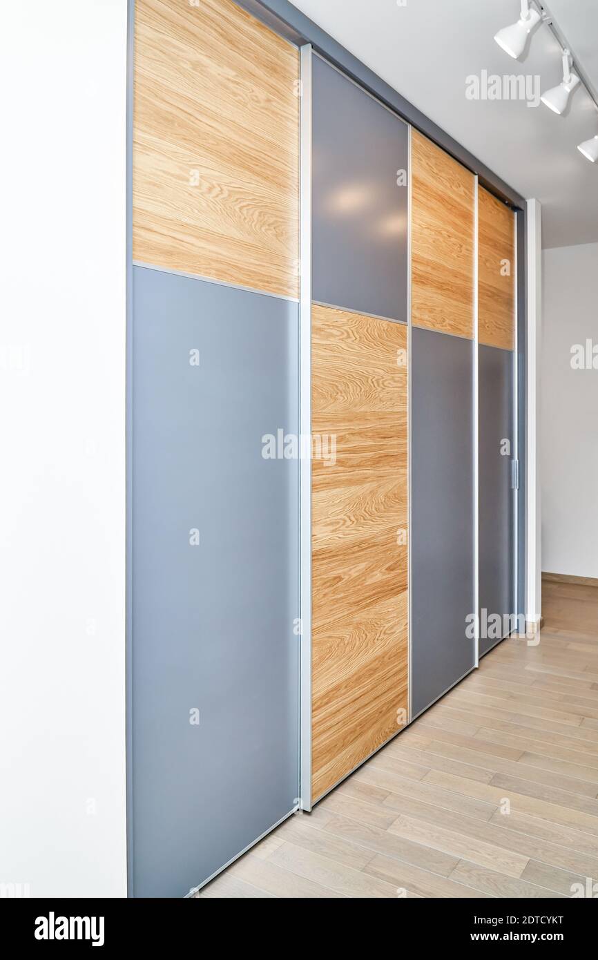 Grande garde-robe élégante avec panneaux de portes coulissantes en lumière  bois de chêne naturel brun aux motifs de texture élégants et blanc parties  grises Photo Stock - Alamy