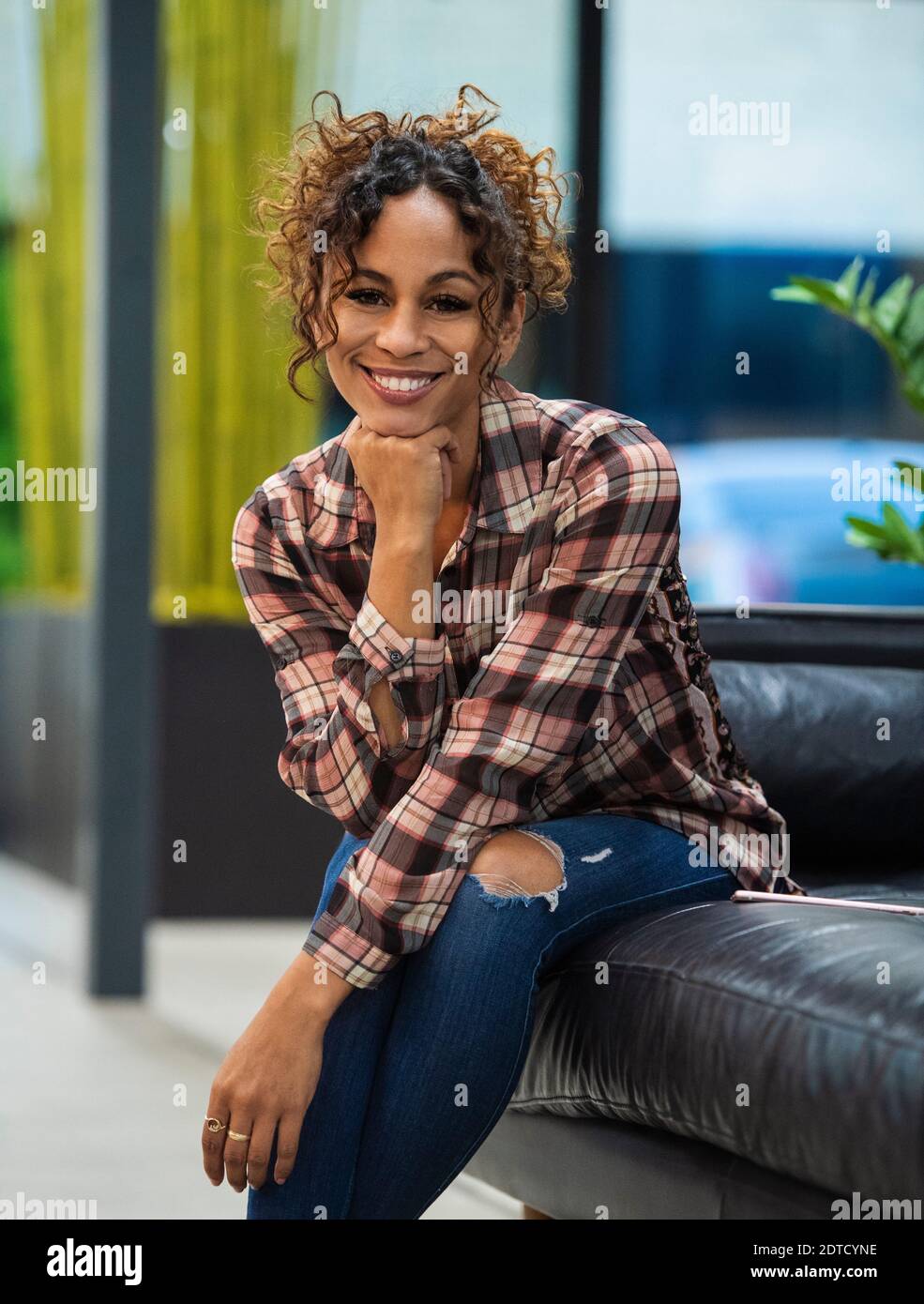 Portrait d'une femme souriante assise sur un canapé au bureau Banque D'Images